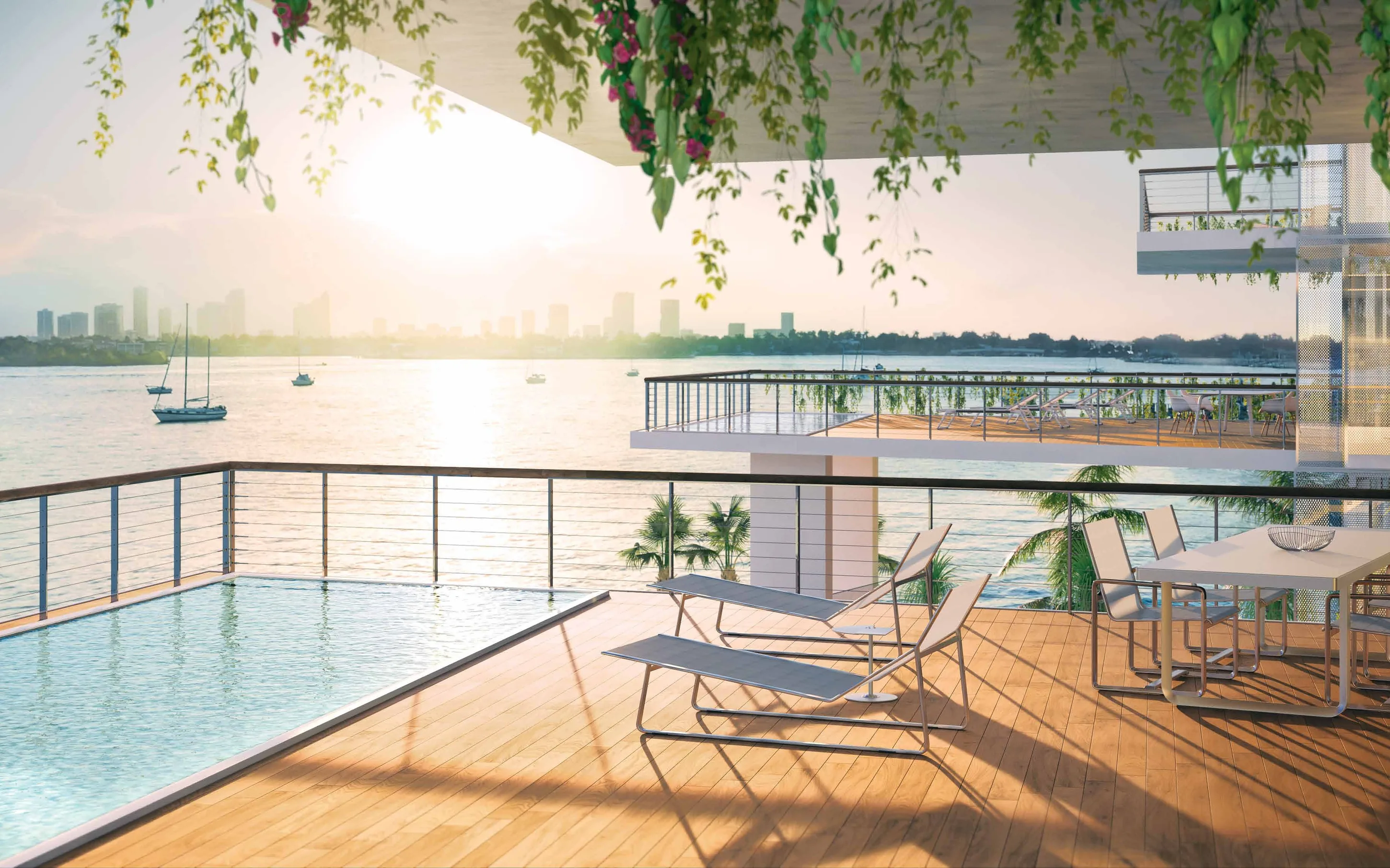 A private terrace pool at the building edge, loungers and a dining table looking west over the bay at sunset